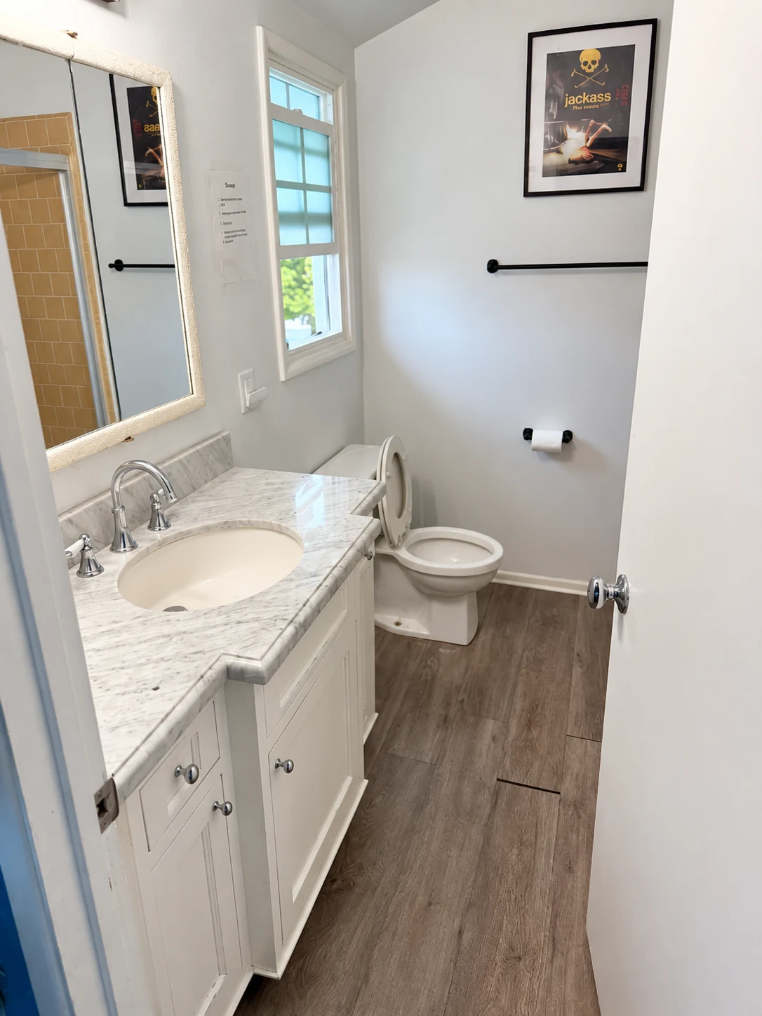 Bright Citronia Recovery bathroom with a marble-top vanity, mirror, toilet, and window