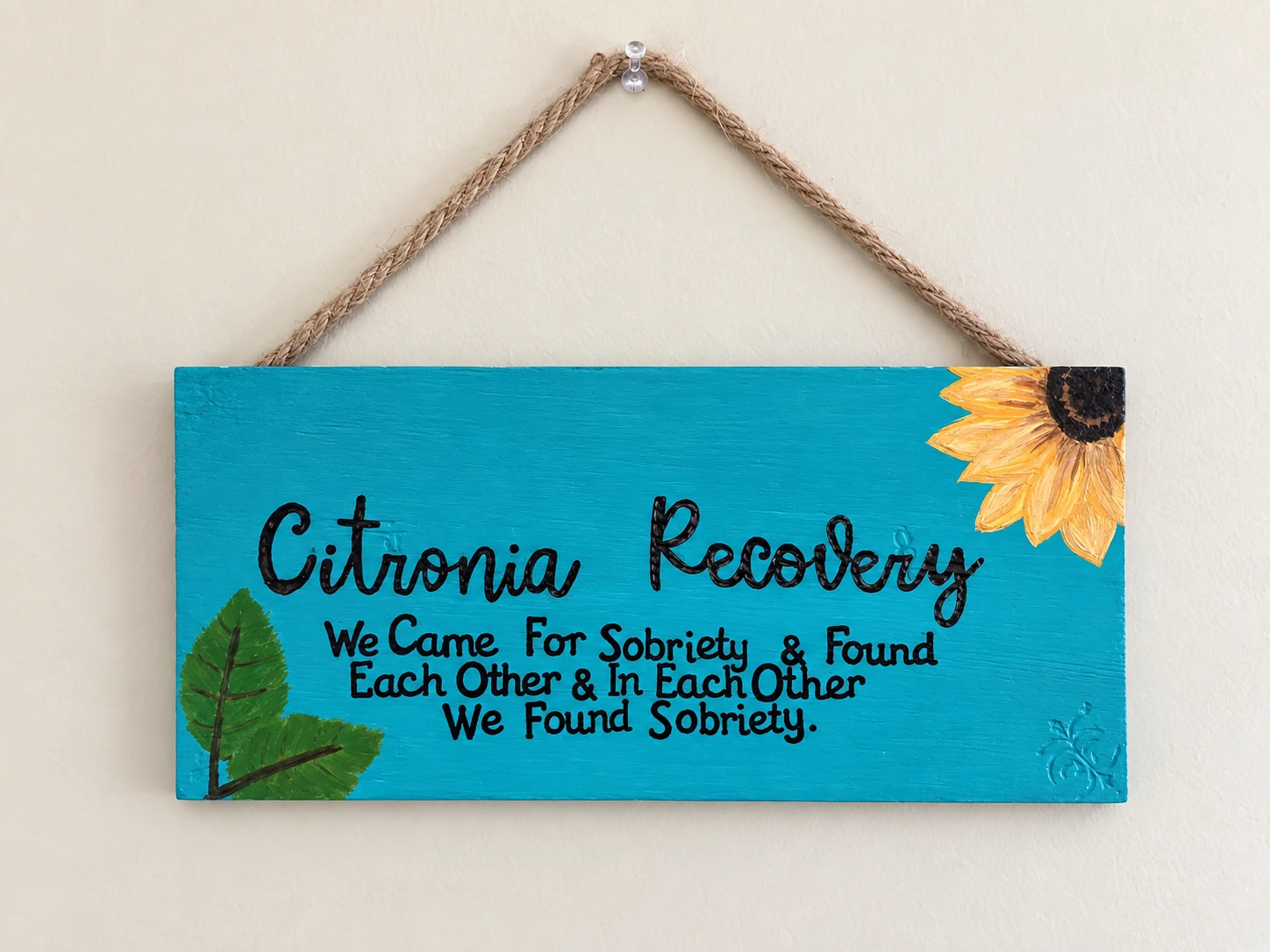 Turquoise handmade Citronia Recovery sign reading: We came for sobriety & found each other & in each other we found sobriety.